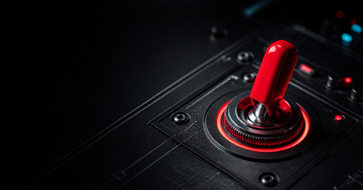 A glossy red toggle switch on a black industrial control panel.